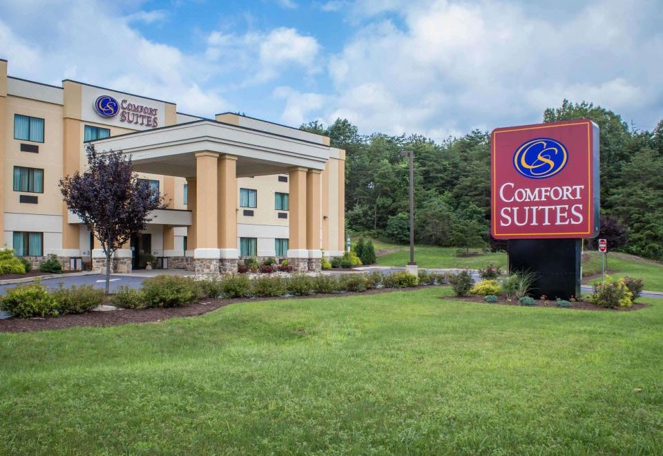 "a large building with a sign that says "" comfort suites "" is surrounded by grass and trees" at Comfort Suites