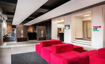 a modern living room with a red couch , black chairs , and a tv mounted on the wall at Metropol Hotel Katowice