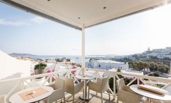 a balcony overlooking the ocean , with several chairs and a table set up for outdoor dining at Paliomylos Spa Hotel