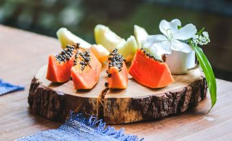 a wooden cutting board with sliced papaya and an apple , placed on a dining table at Work Hotel São Leopoldo