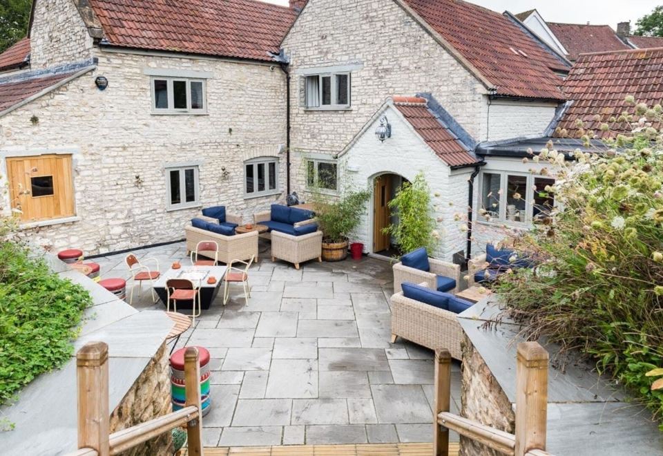a courtyard with a stone patio , outdoor seating , and tables is shown in front of a stone building at The Litton
