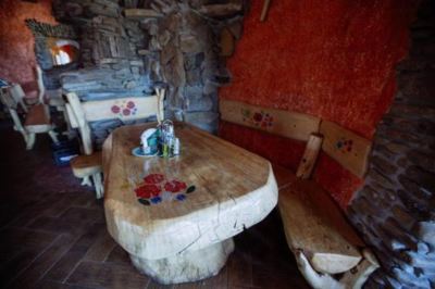 a wooden dining table with a bench and chairs in front of a stone wall at Troll