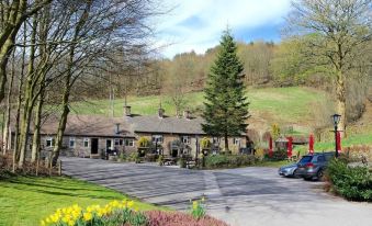 a parking lot with a car parked in front of a building , surrounded by trees and grass at The Lamb Inn