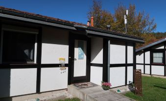 a small house with white and black siding , a door , and a porch , under a clear blue sky at Scout