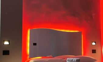 a bed with a white headboard and colorful lighting is in a room with two light fixtures on the wall at The Lux