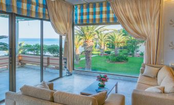 a living room with a couch , coffee table , and sliding glass doors leading to an ocean view at Golden Sand Hotel