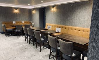 a modern conference room with wooden tables , chairs , and a gray wall , along with additional seating for attendees at Kilmorey Arms Hotel