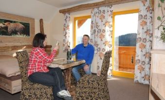 a man and a woman are sitting at a dining table in a hotel room , enjoying a glass of wine together at Hohenstein