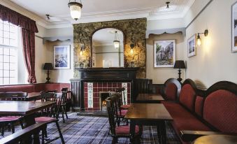 a cozy dining room with a fireplace , wooden chairs and tables , and various decorations on the walls at The Bulls Head