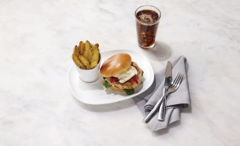 a white plate with a hamburger , fries , and a cup of soda on a dining table at Even Hotel Rockville - Washington, DC Area, an IHG Hotel