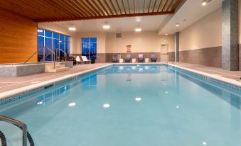 an indoor swimming pool with a wooden ceiling , surrounded by lounge chairs and a ceiling fan at Running Aces Hotel & Casino Trademark Collection by Wyndham