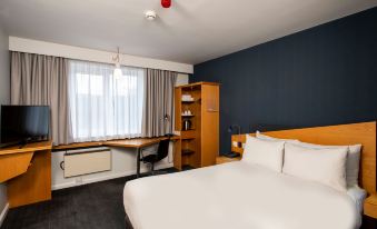 a hotel room with a large bed , white sheets , and a desk with a computer on it at Holiday Inn Express East Midlands Airport