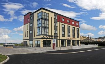 a modern building with multiple floors , situated on a city street under a blue sky with scattered clouds at Ramsey Park Hotel