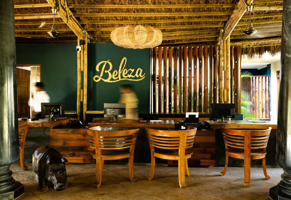 "a restaurant with wooden chairs and tables , a sign on the wall that says "" beleza "" in yellow" at Beleza by the Beach