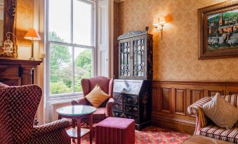 a cozy living room with wooden furniture , including a chair , a couch , and a coffee table at Makeney Hall Hotel