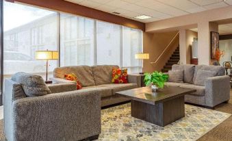 a living room with gray couches , a coffee table , and lamps , as well as a staircase in the background at Siegel Select Bartlett Extended Stay in Tennessee