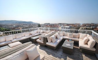 a rooftop patio with multiple couches and chairs arranged in a seating area , providing a comfortable outdoor space for relaxation and socializing at Splendid Hotel & Spa Nice