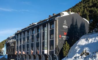 a large , modern hotel building with multiple floors and balconies , situated in a snowy environment at Hotel Austria