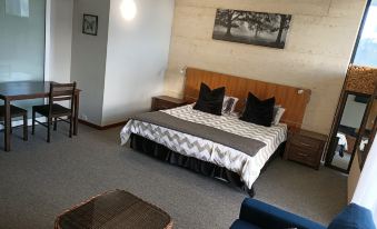 a modern bedroom with a large bed , couch , and table , along with a dining area and living area at Yanchep Inn