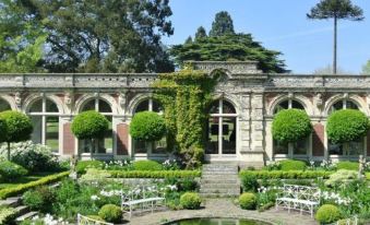 a beautiful garden with a pond , green trees , and white chairs surrounded by lush greenery at Brasteds