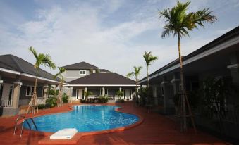 a large swimming pool is surrounded by a house and palm trees with a red brick patio at Rongsang Resort