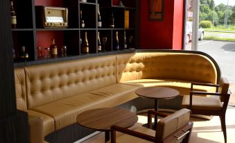 a cozy living room with leather couches , wooden chairs , and wine bottles on shelves , creating a warm and inviting atmosphere at Le Grand Hotel