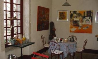 a dining room with a table set for breakfast , surrounded by paintings on the walls at Le Petit Paris