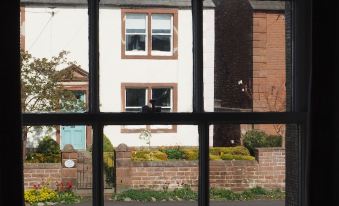 a window view of a brick building with a flower garden and a brown house in the background at The Shepherds Inn
