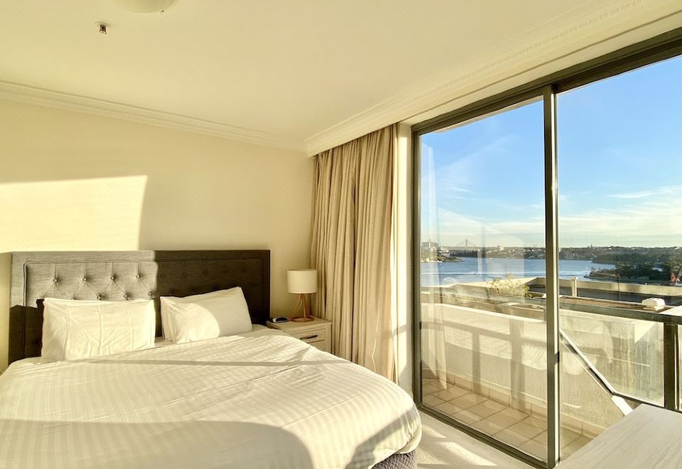 a hotel room with two beds and a balcony offering a view of the ocean at Milson Serviced Apartments