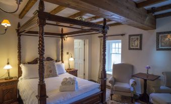 a cozy bedroom with a four - poster bed , white linens , and a lamp on the nightstand at The Peak Hotel