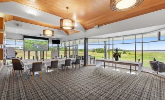 a large , open room with wooden ceiling and floor , filled with rows of chairs and tables at 13th Beach Golf Lodges