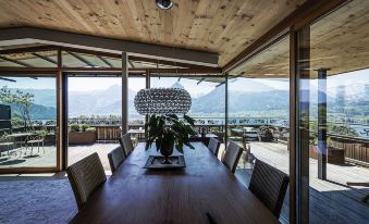 a wooden dining table with chairs and a large chandelier hanging from the ceiling , overlooking a beautiful mountainous landscape at The View