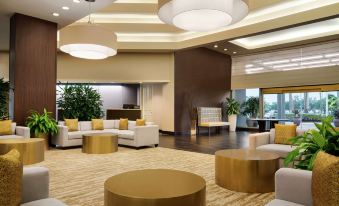 a modern , well - lit hotel lobby with various seating arrangements and chandeliers , creating a comfortable and inviting atmosphere at Hilton Melbourne, FL