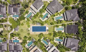 aerial view of a resort with multiple buildings and a pool surrounded by greenery , including palm trees at Robinson Khao Lak