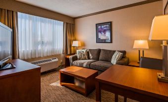 a living room with a couch , two tables , and a tv . also a bed in the room at Best Western Plus Barclay Hotel