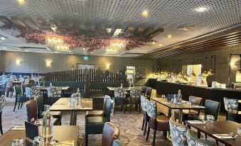 a large , well - lit restaurant with multiple dining tables and chairs , as well as a bar area at Woodland Grange