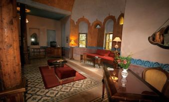 a living room with a red couch , wooden coffee table , and arched windows , decorated with lamps and flowers at Al Moudira Hotel