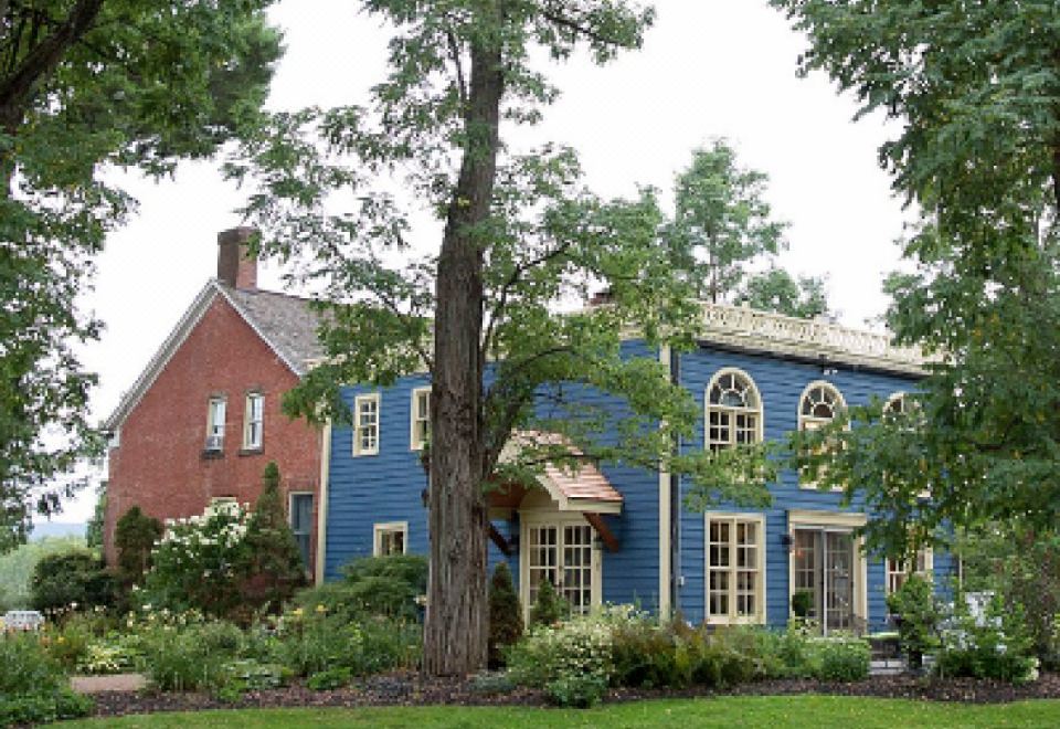 a blue house with a red brick house and a tree in front of it at Elmrock Inn
