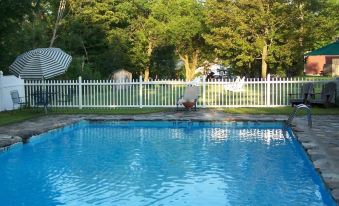a large outdoor swimming pool surrounded by trees , with a white fence surrounding the pool area at Three Mountain Inn
