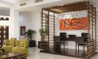 a modern office space with a green couch , wooden desk , and framed art on the wall at Hotel Mexico Plaza Irapuato