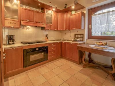 a modern kitchen with wooden cabinets , a tile floor , and a window with curtains above it at Messi