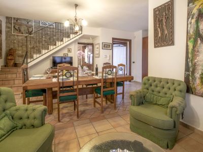 a spacious living room with wooden furniture , including a dining table and chairs , a couch , and a television at Messi