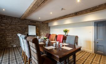 a conference room with a long table , chairs , and a vase of flowers in the center at The Greyhound Hotel