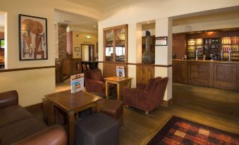 a cozy living room with wooden furniture , including couches and chairs , arranged around a coffee table at Premier Inn Tamworth South