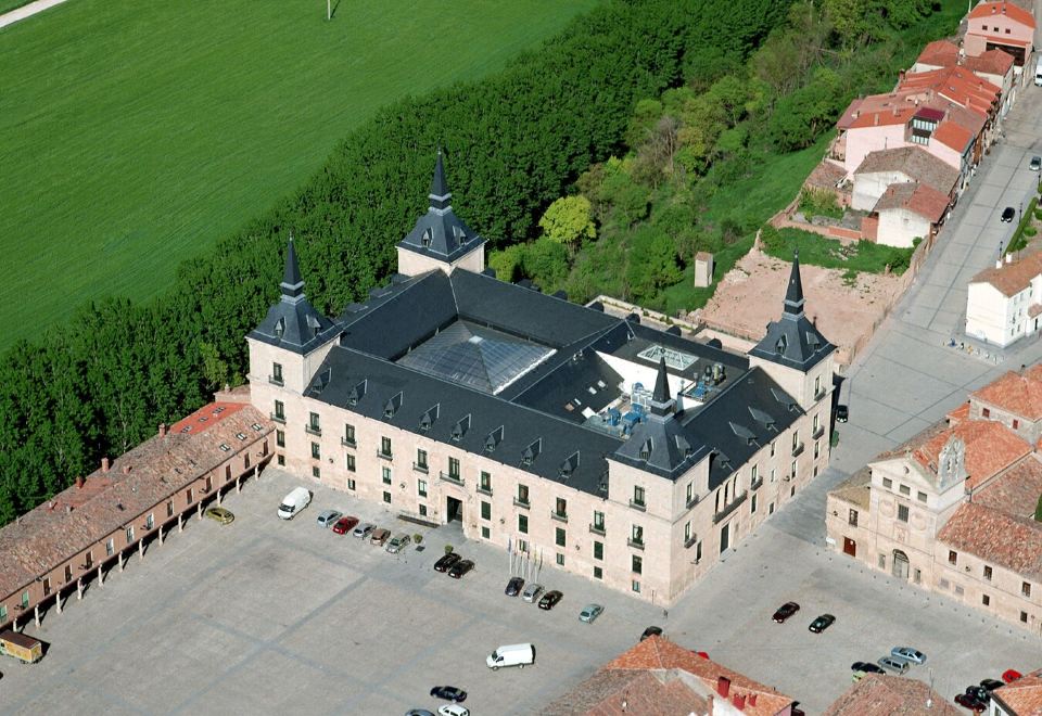 a large building with a traditional european architectural style is surrounded by green grass and trees at Parador de Lerma