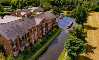 a large building with a boat in front of it and a river running alongside it at Lion Quays Resort