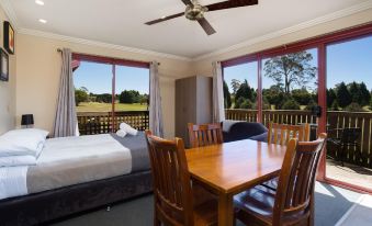 a bedroom with a bed and wooden table is shown with a ceiling fan and large windows at Aspect Tamar Valley Resort