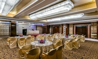 a large banquet hall with round tables covered in gold tablecloths and chairs arranged for a formal event at The Regenza by Tunga