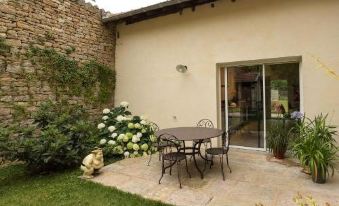 a backyard with a small patio set , flowers , and a sliding glass door leading to an outdoor dining area at Le Cercle Chambres Climatisees