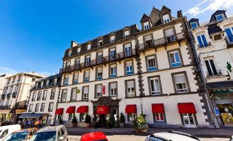 a large white building with red awnings and balconies , surrounded by cars parked on the street at Hôtel du Parc